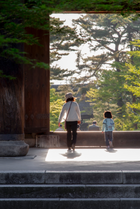 お寺の門をくぐる親子